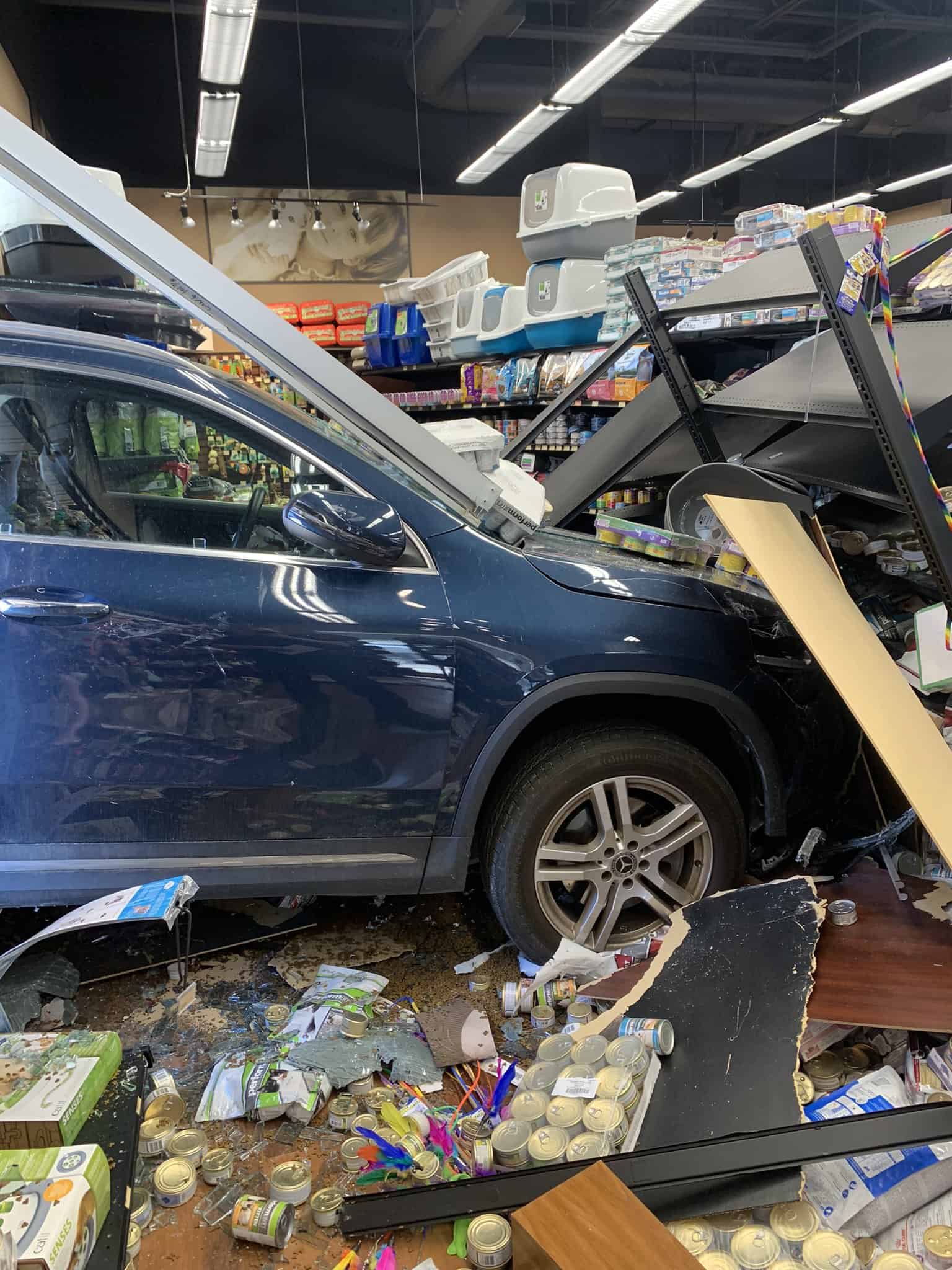The front end of a vehicle sits in the aftermath of a destroyed pet store after crashing into it.