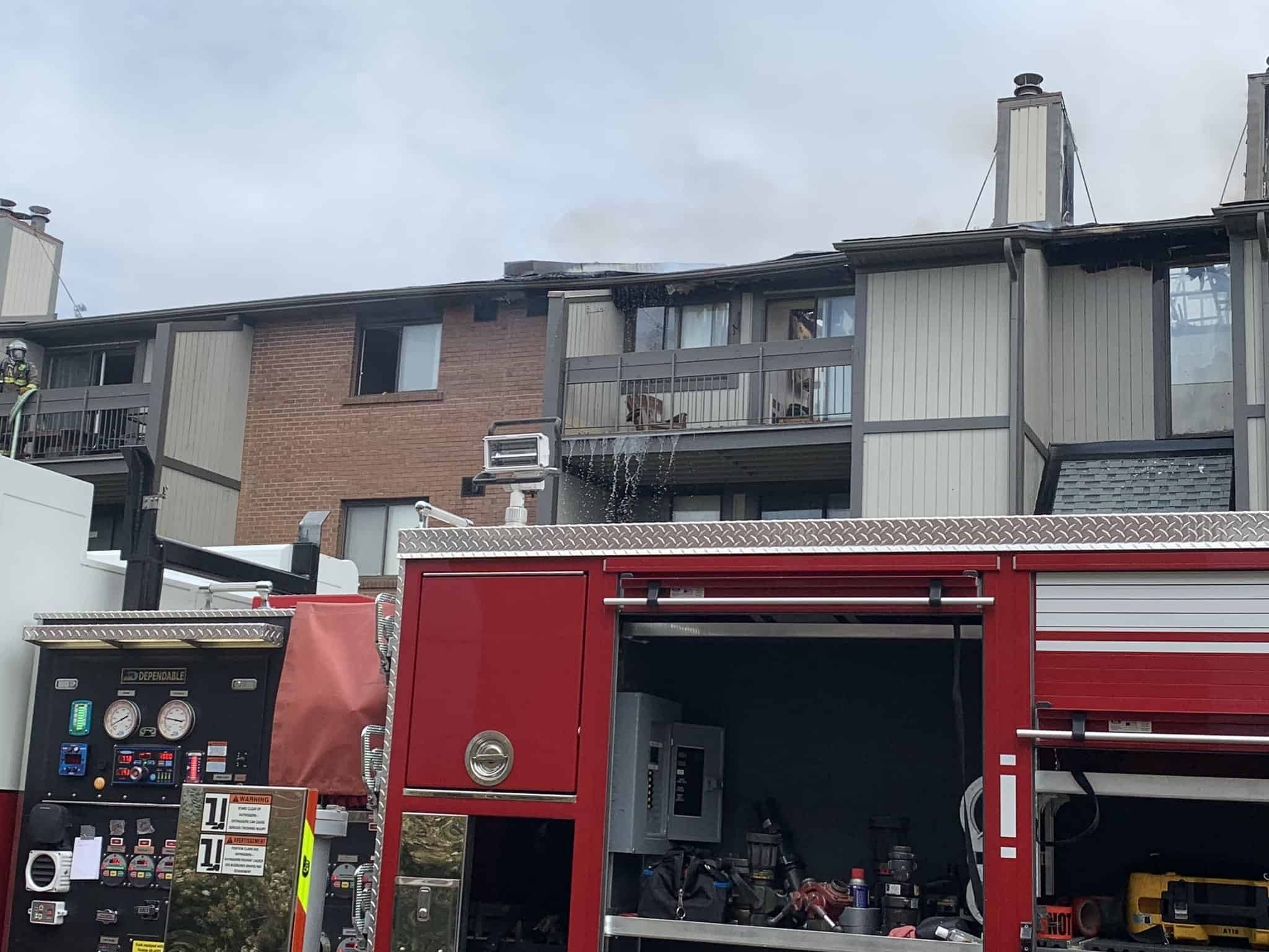 Water dripping from the edge of a balcony as a fire truck sits in the foreground.