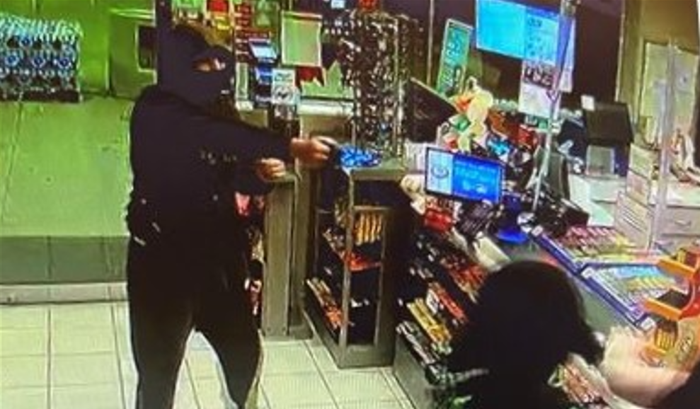 robber holding gun up at gas station worker
