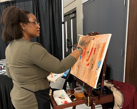 Artist Leequette (Lala) Santiago paints a scene from the opening ceremonies live during the Black Vendor Village.